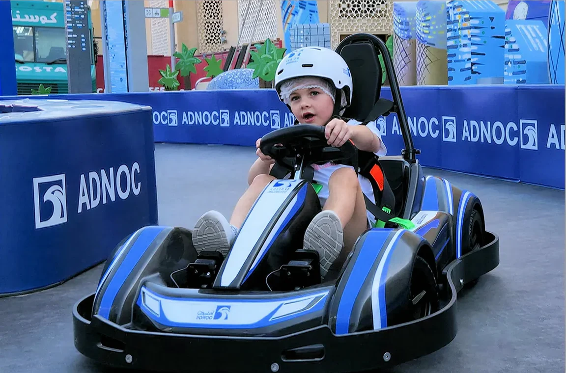 A child drives an electric kart at an ADNOC brand activation