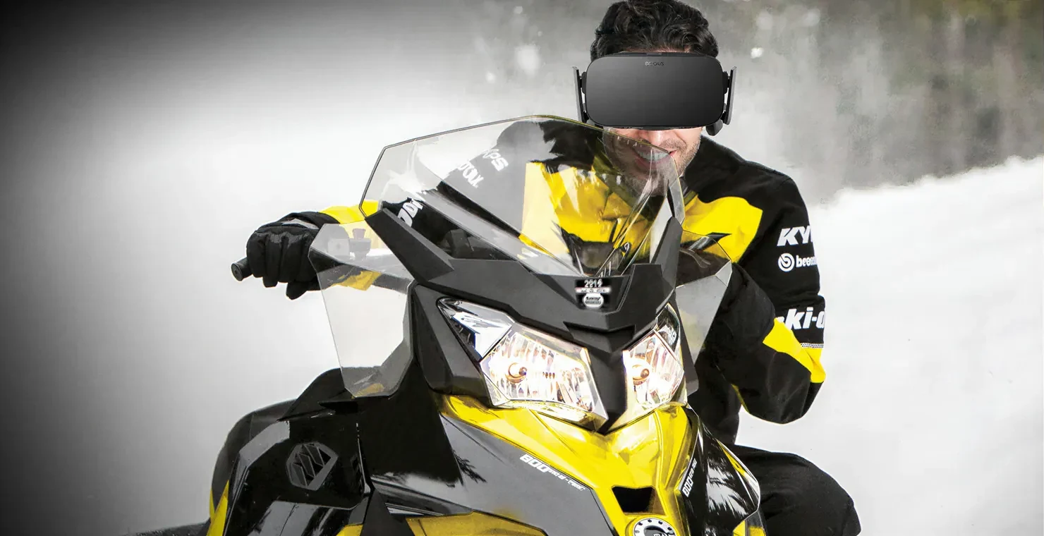 A rider in a VR headset on a snowmobile simulator