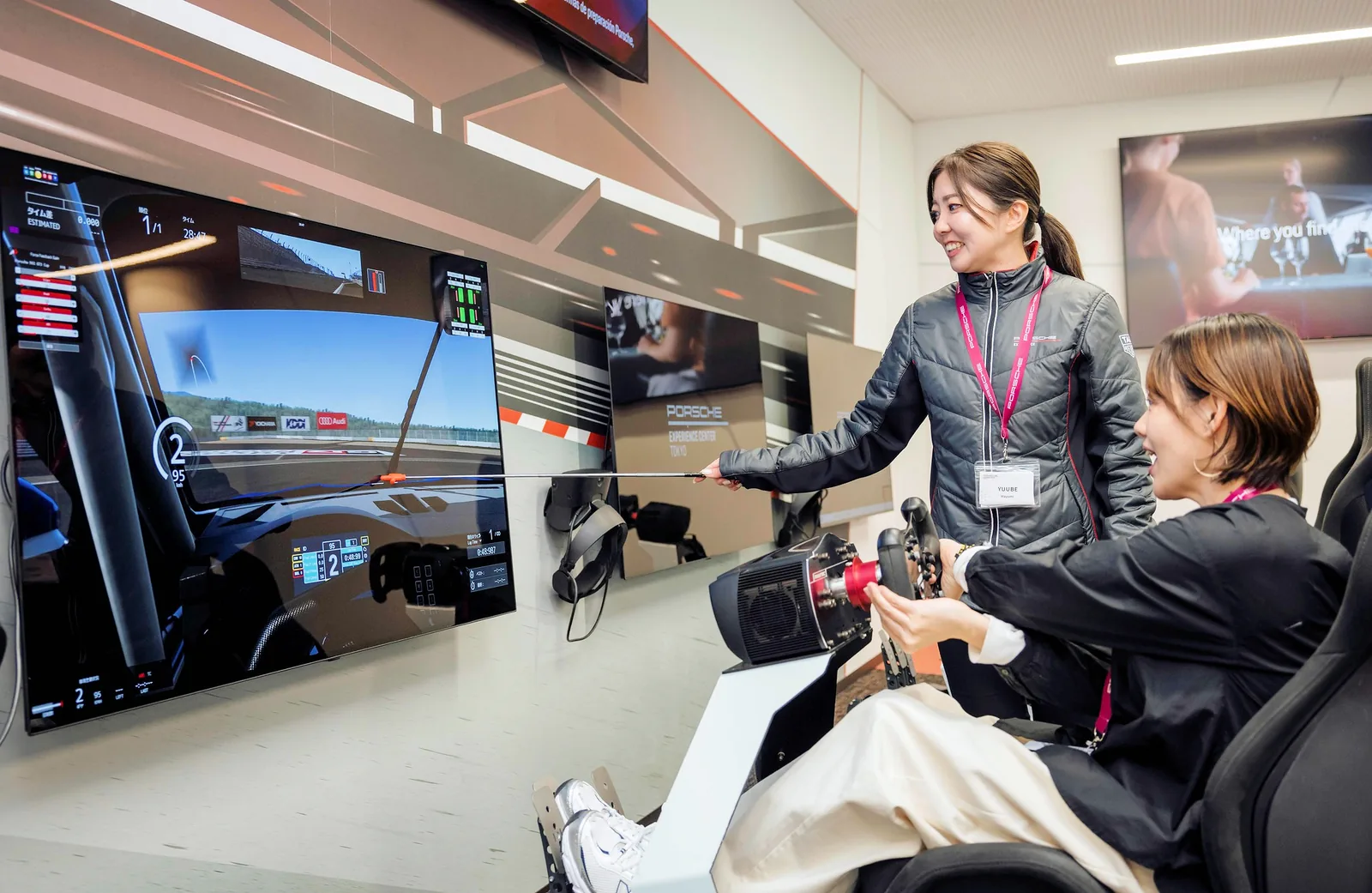 An Excape coach guides a guest on a racing simulator at the Porsche Experience Center Tokyo