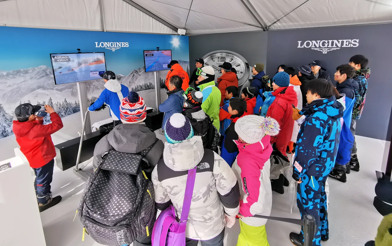 Children in ski gear at a Longines winter activation, watching the simulator screens