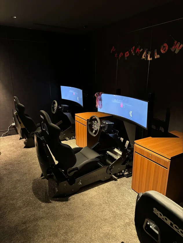 A private racing room with a Sparco rig and an ultrawide screen