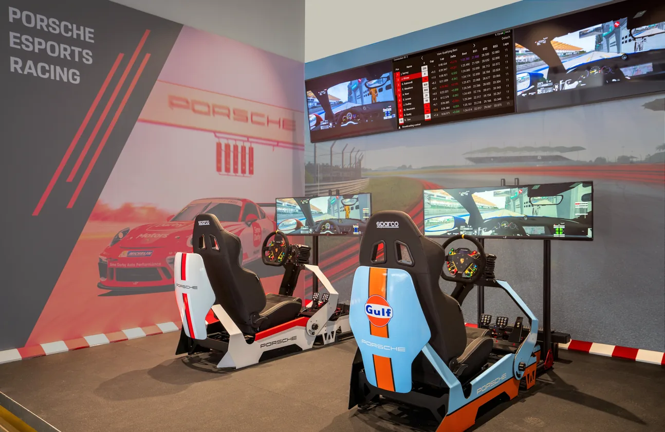 The Porsche Esports Racing space — Gulf-liveried rigs against a Porsche mural