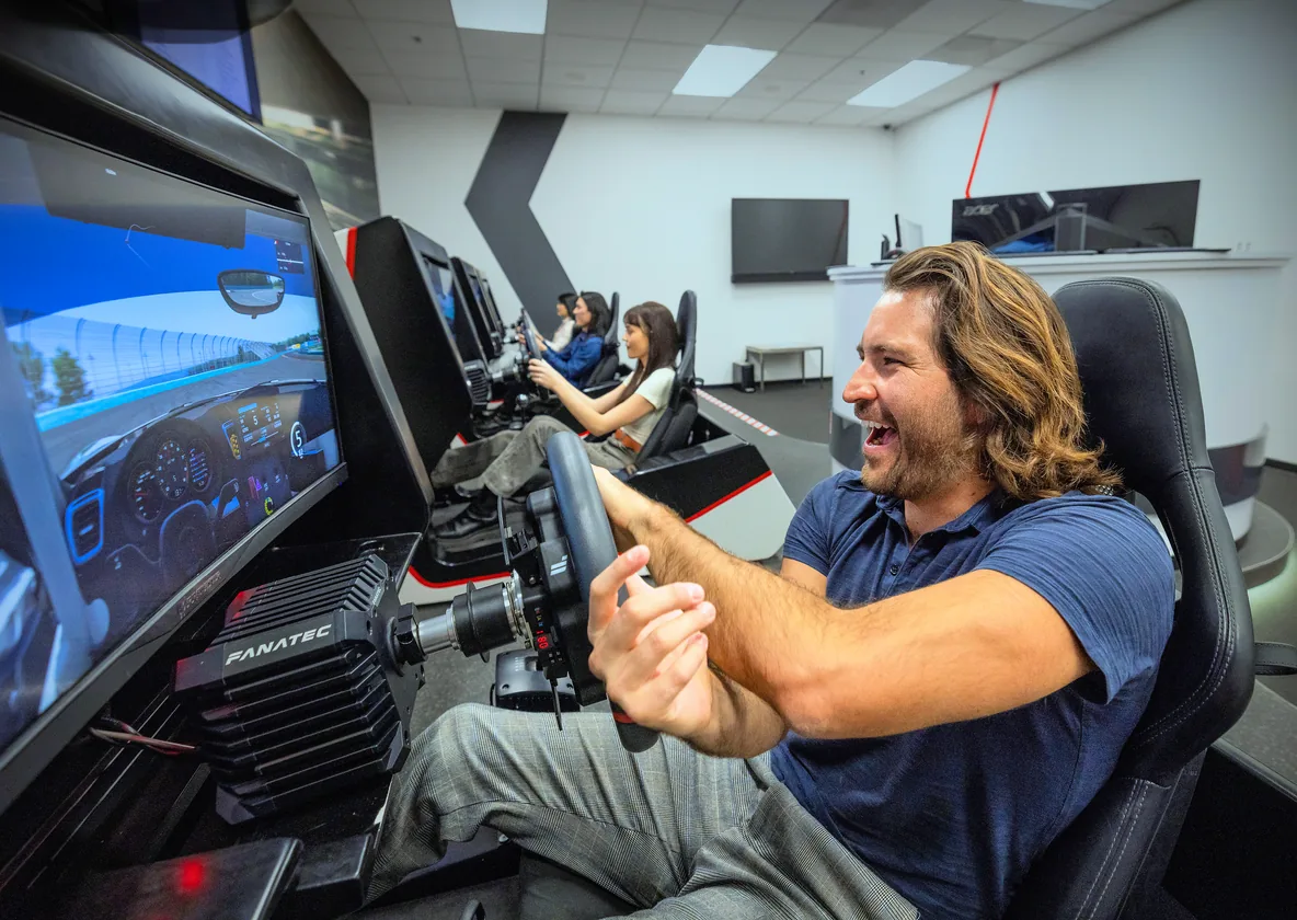 A driver laughing at the wheel of a Fanatec-equipped esports rig
