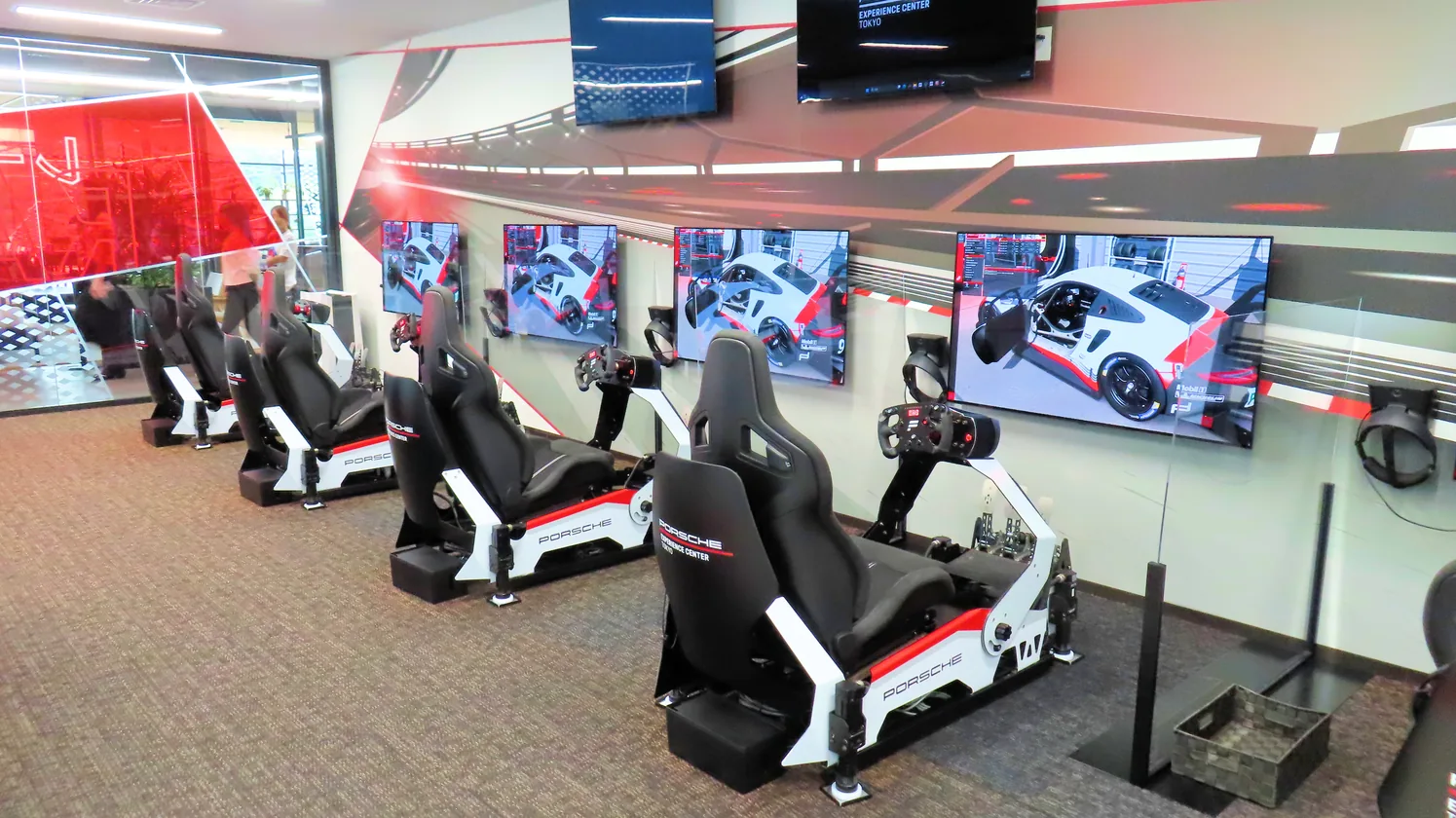 A row of Porsche esports rigs along a glazed façade